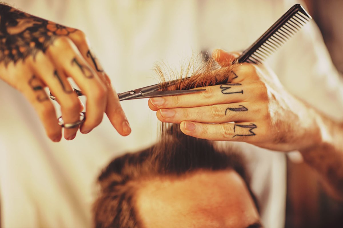 A barber cutting hair with scissors and a comb